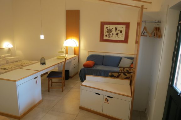 Kleine Wohnung mit blauer Couch, Tisch, Stuhl und gemütlicher Beleuchtung.