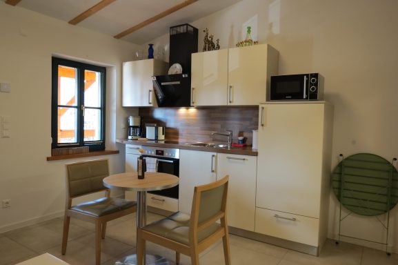 Kleine moderne Küche mit Tisch und Stühlen, Küchenschränken und Geräten.