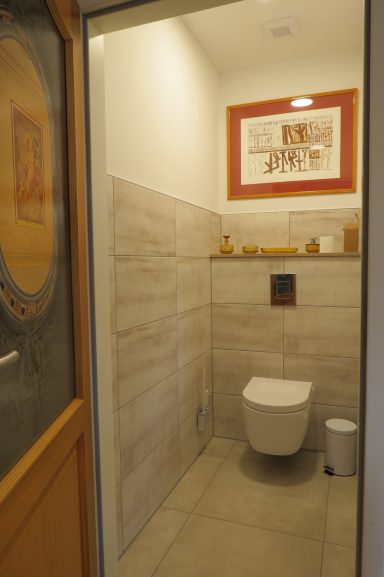 Sauberes, modernes WC mit Fliesen und Holzdetails in einem hellen Raum.